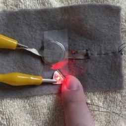 I was pretty sure that the battery pack was the issue so I ripped it out and just taped down the batttery and conductive thread. I used a wire to finish the circut so I could get a good idea of if it was working well before I moved forward